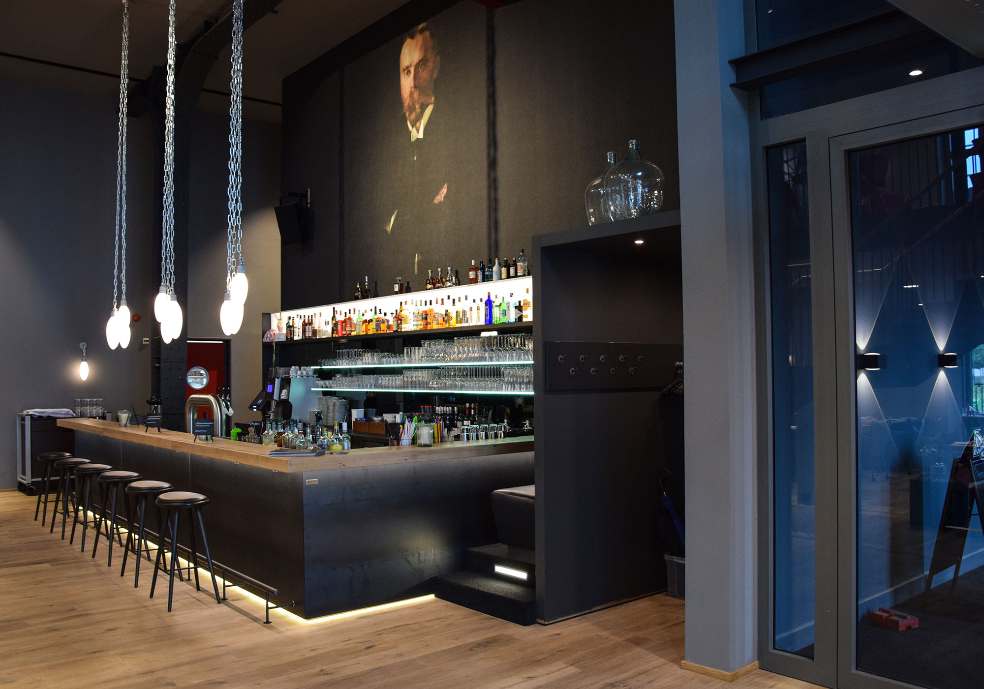 Moderne Bar mit Hängelampen und regalen voller Flaschen und Gläser