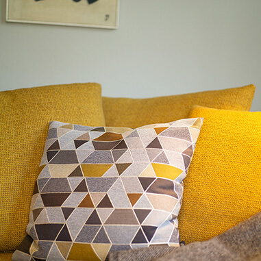 Gelbe Sofakissen mit geometrischem Muster im gemütlichen Wohnzimmerambiente