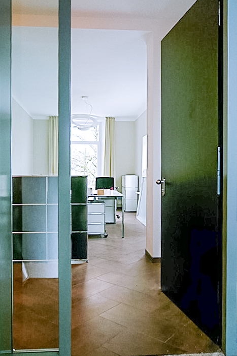Moderner Büroraum mit weißem Schreibtisch, Hängelampe und Fensteransicht