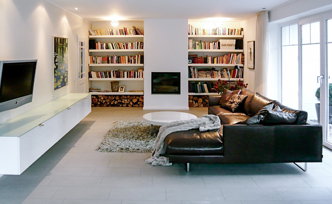 Modernes Wohnzimmer mit Ledersofa, Kamin, Bücherregalen und großem Fenster für viel Tageslicht