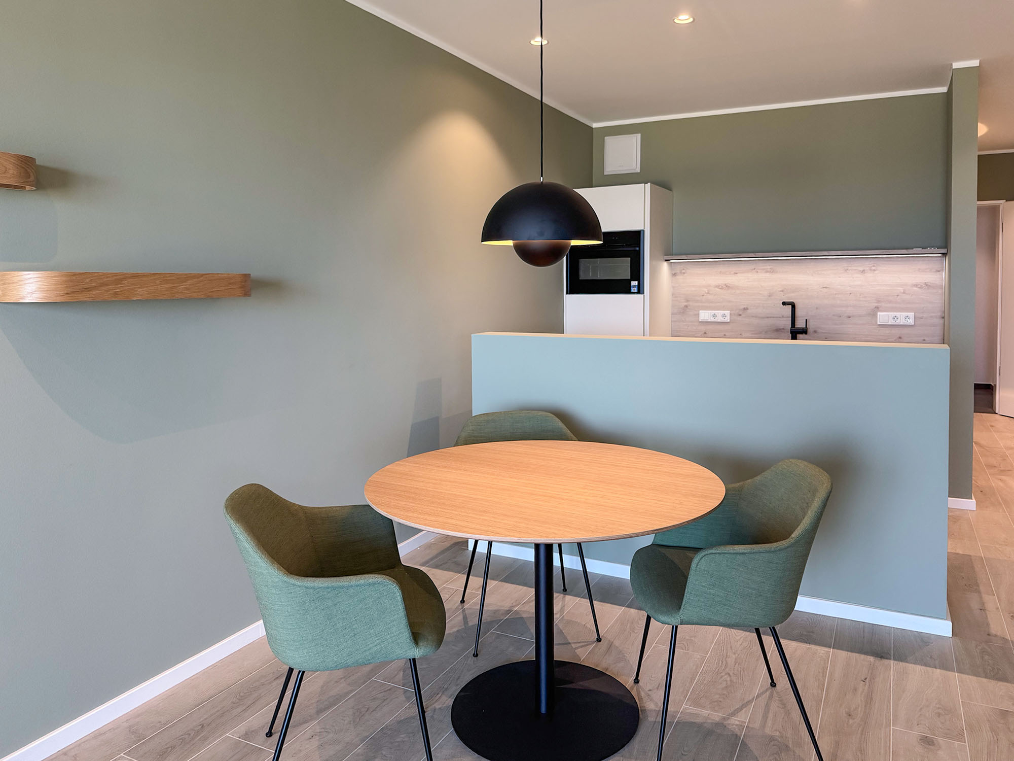 Moderne Küche mit Holz-Esstisch, grünen Stühlen und stilvoller Hängelampe